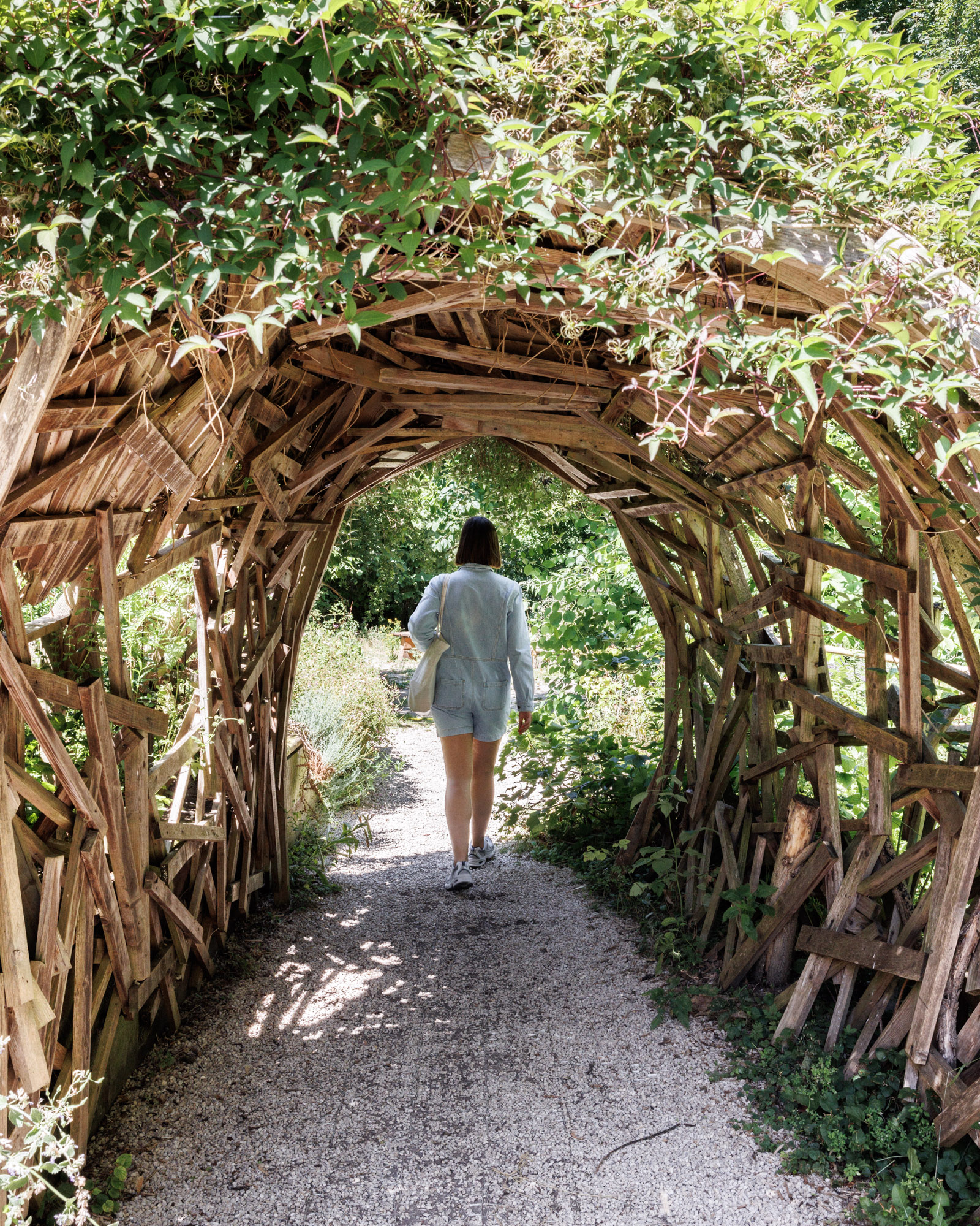 Jeune femme traversant une structure fait de bois et de plantes