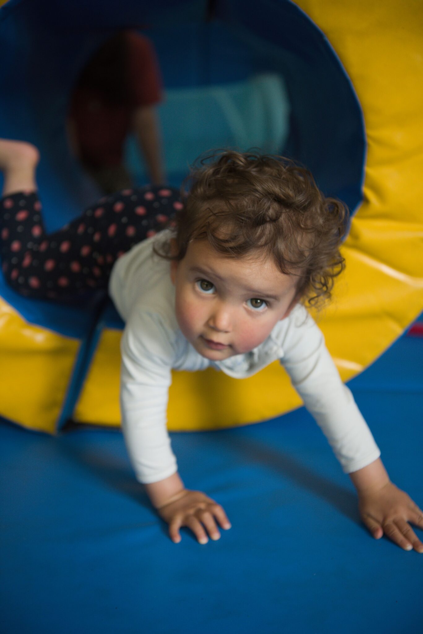 Enfant sortant d'une structure en mousse jaune et bleue, lors d'un atelier de motricité à Little Villette.