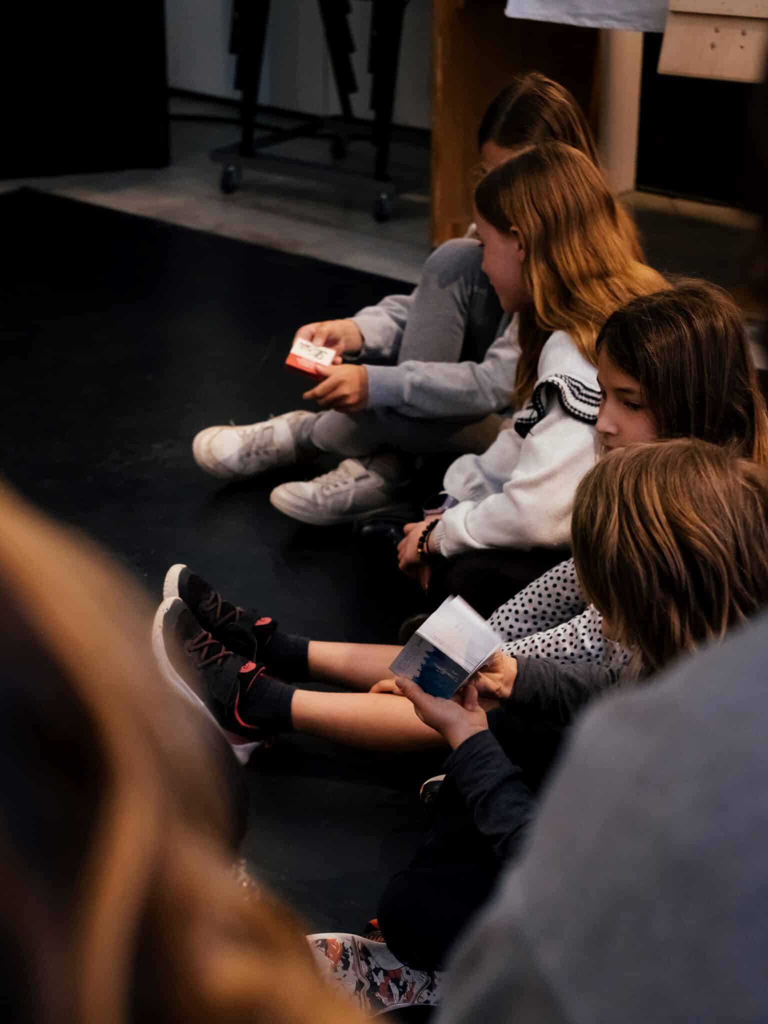 Enfants assis par terre en train de regarder des petits folioscopes, pour apprendre les bases du stop motion.