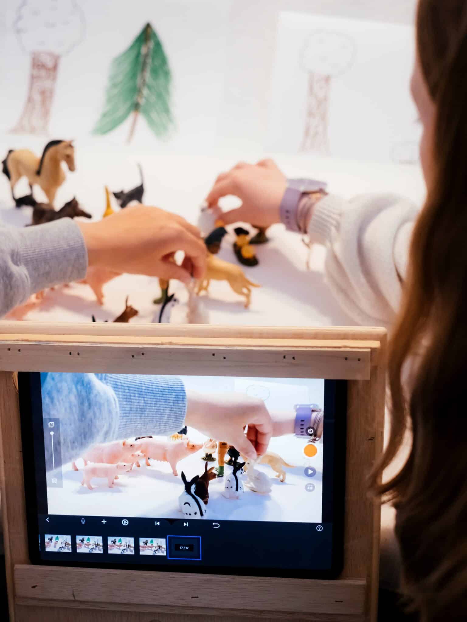 Mains d'enfants positionnant quelques figurines d'animaux pour faire un film en stop motion