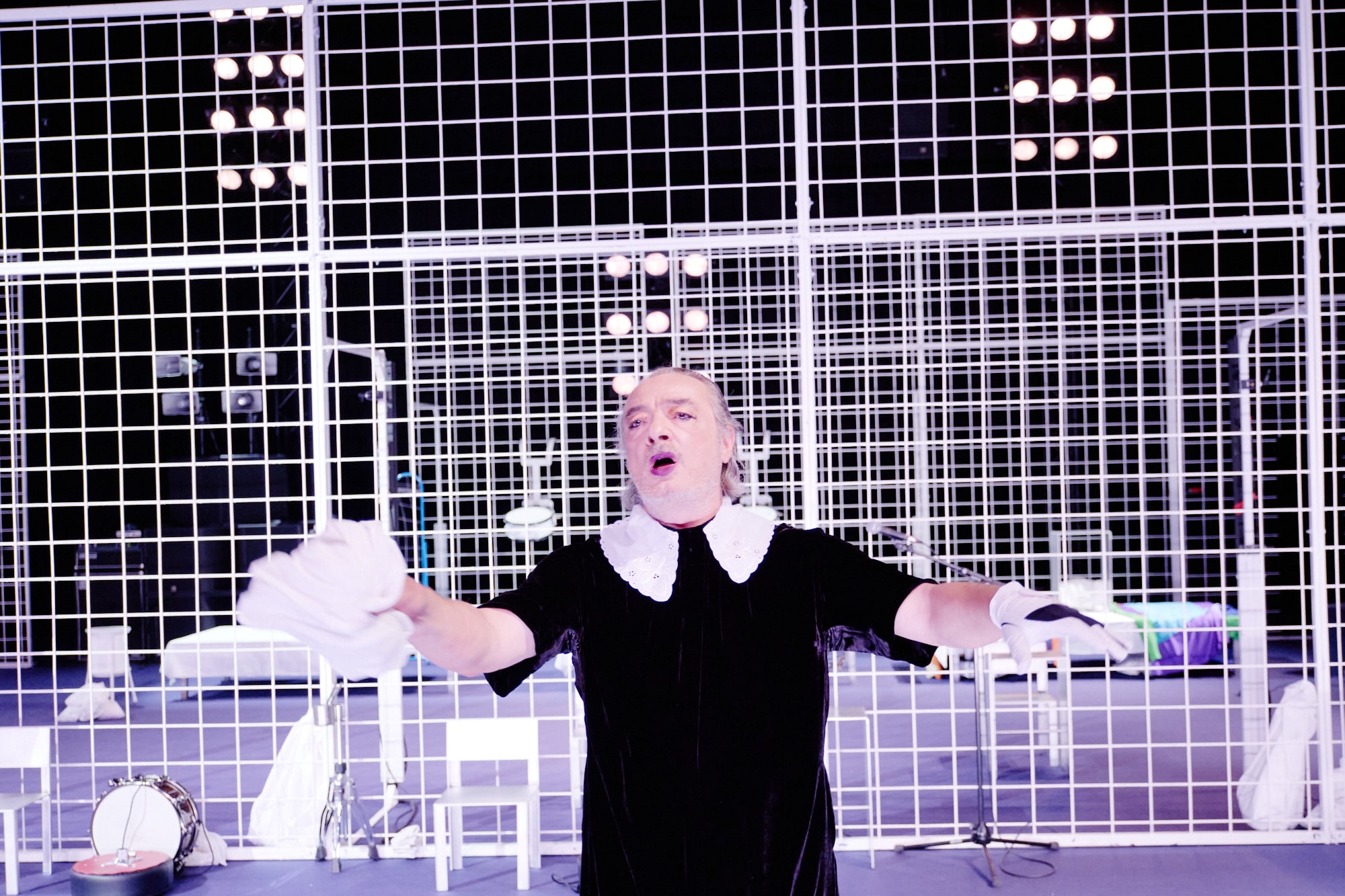 NÔT – Marlene Monteiro Freitas : interprète en costume noir et col blanc en action devant une structure scénique en quadrillage.