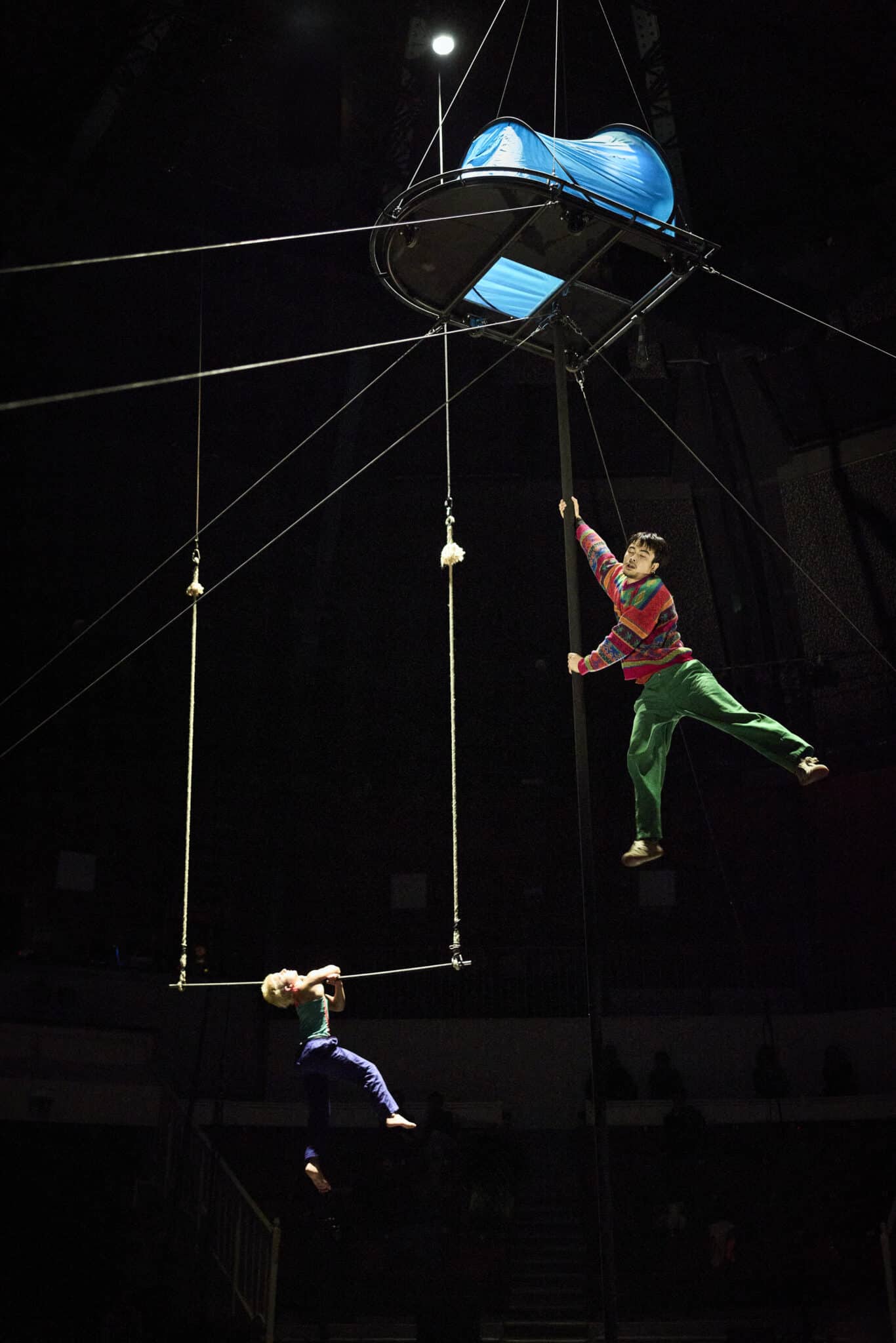 Performance aérienne du spectacle Spectacle de fin d’études de la 37e promotion du CNAC, mis en piste par Halory Goerger : deux artistes évoluent sur un mât et une corde sous une structure suspendue bleue.