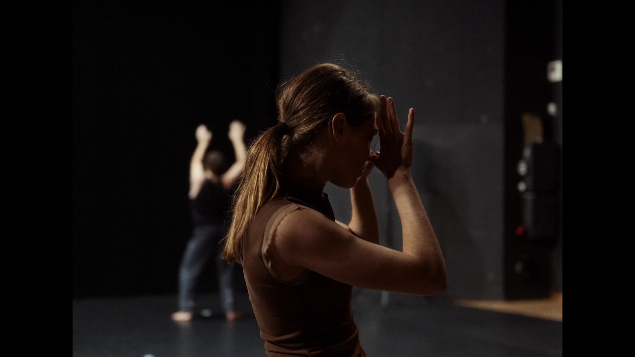 Visuel du spectacle Éclats de Léa Vinette : interprète en profil, les mains relevées devant le visage, en arrière-plan une autre personne en mouvement.