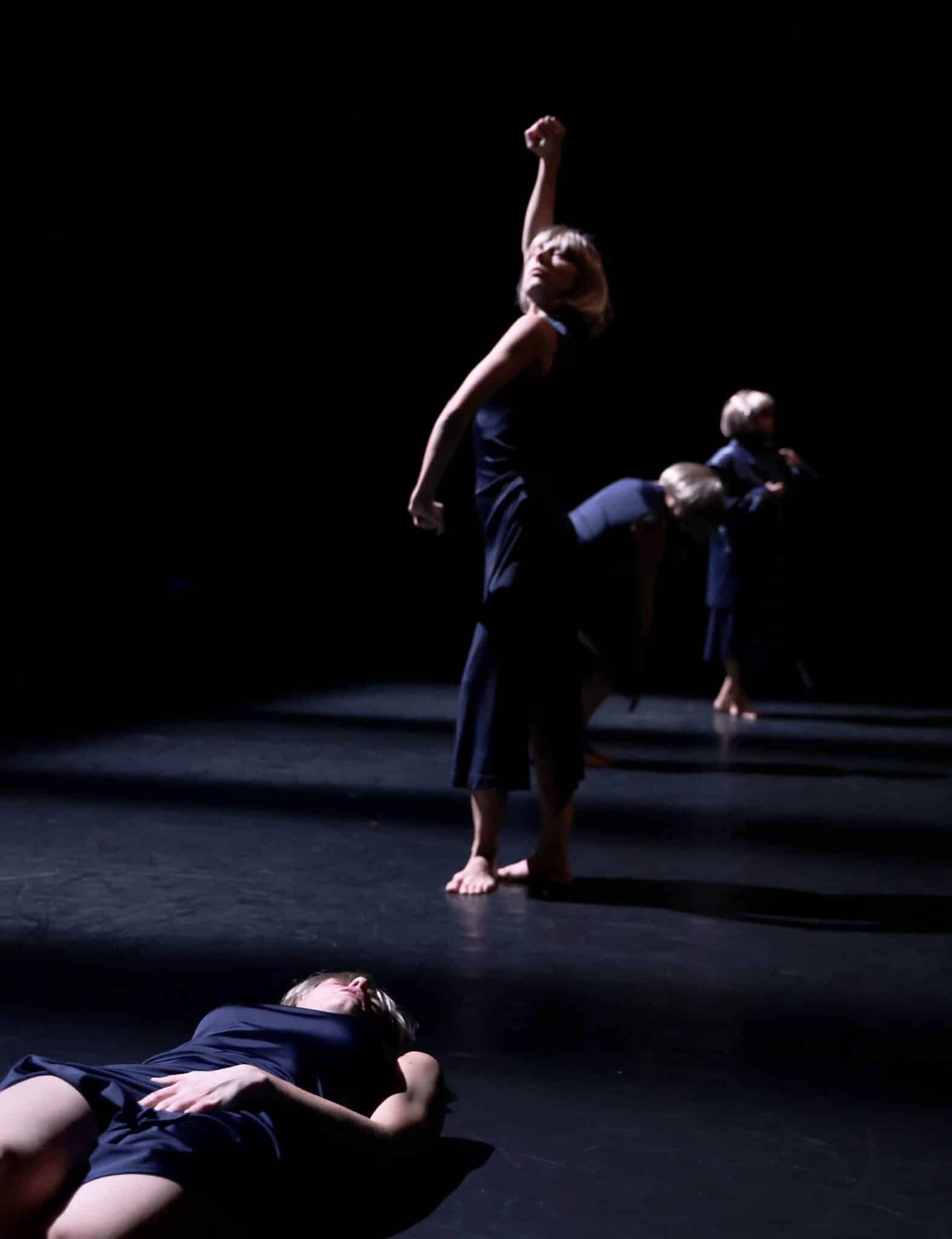 Danseuses en robe sombre exécutant une chorégraphie sur scène dans le spectacle Commençons par faire l’amour de Laura Bachman.