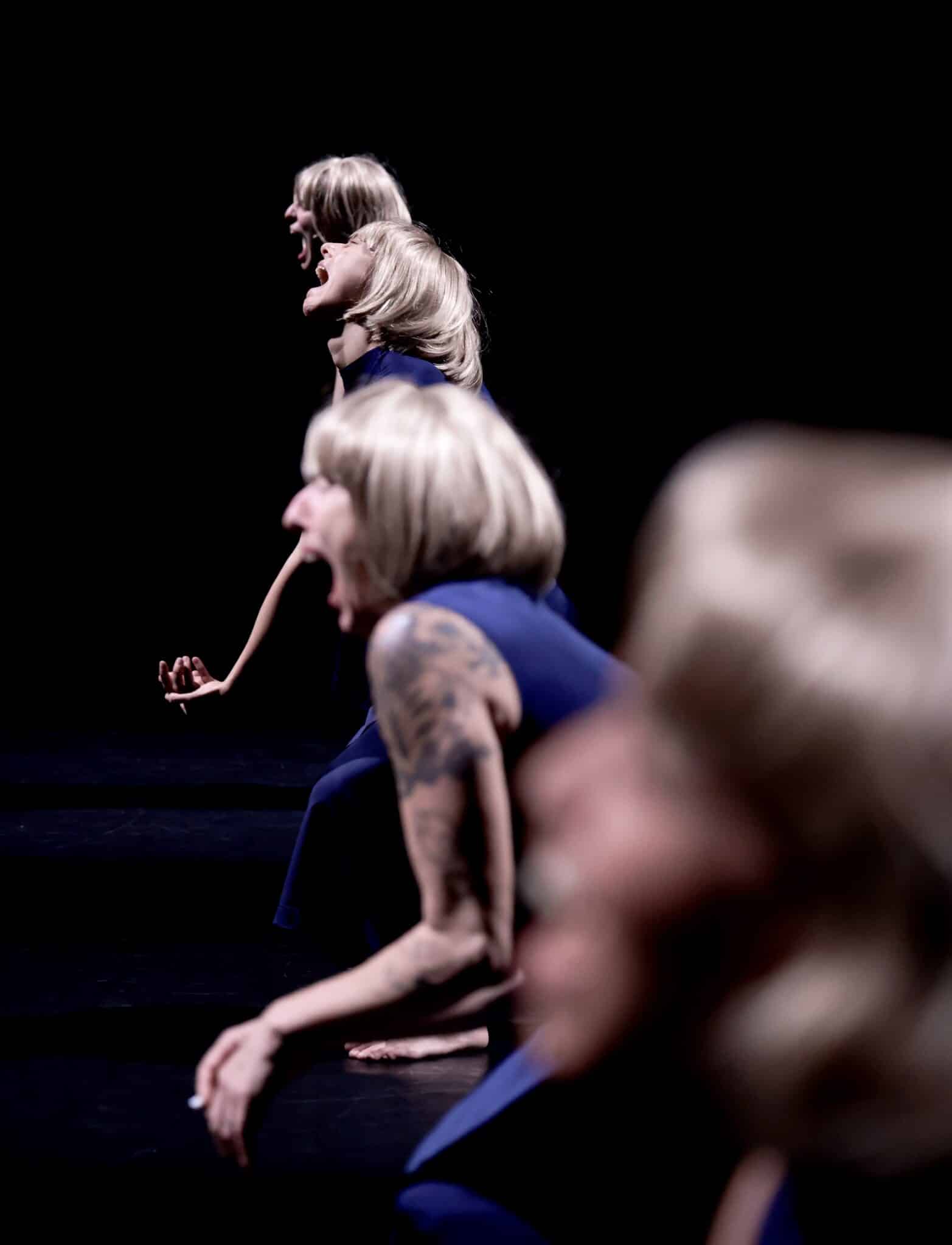 Danseuses en robe sombre exécutant une chorégraphie sur scène dans le spectacle Commençons par faire l’amour de Laura Bachman.