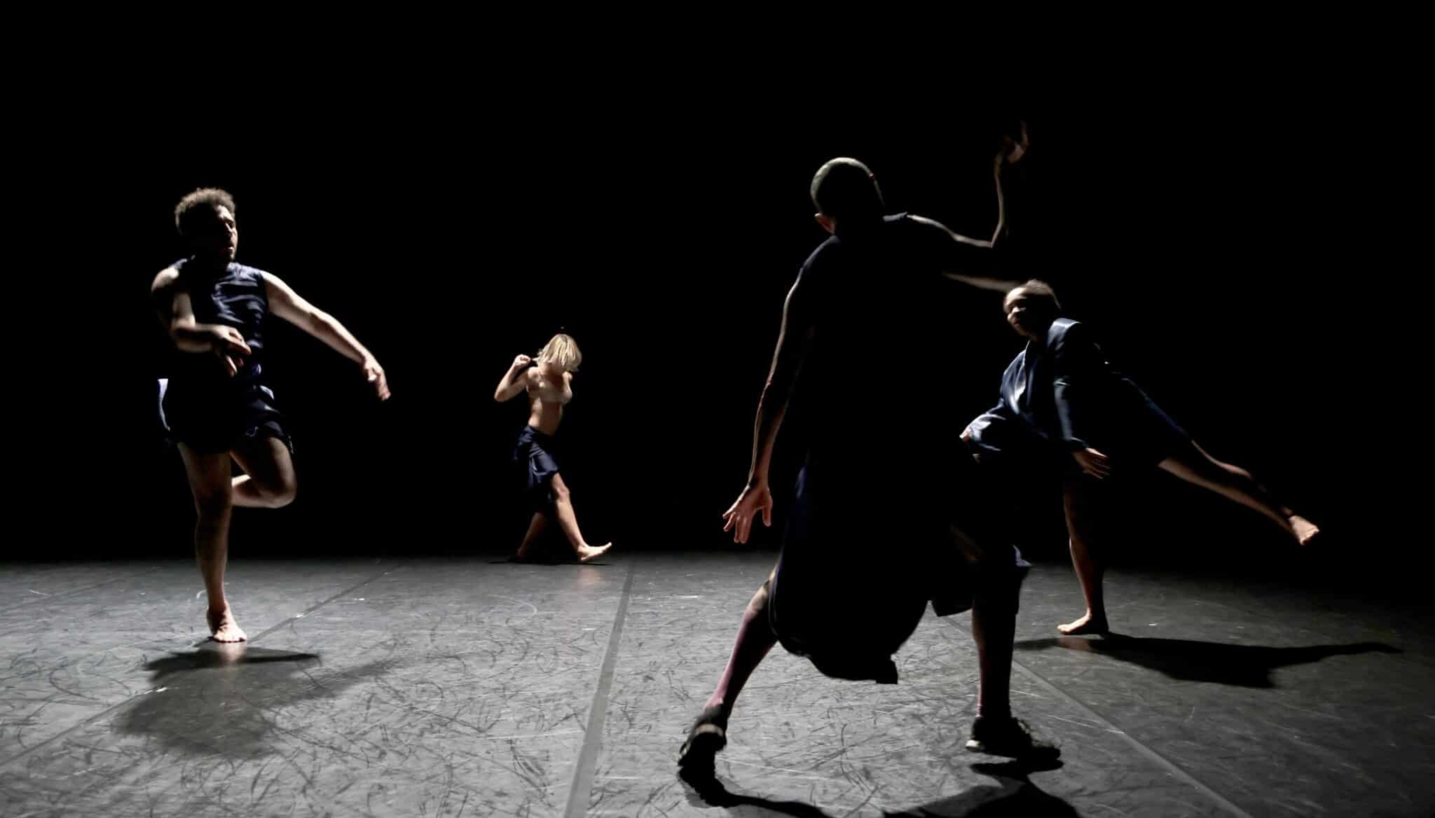 Danseuses en robe sombre exécutant une chorégraphie sur scène dans le spectacle Commençons par faire l’amour de Laura Bachman.