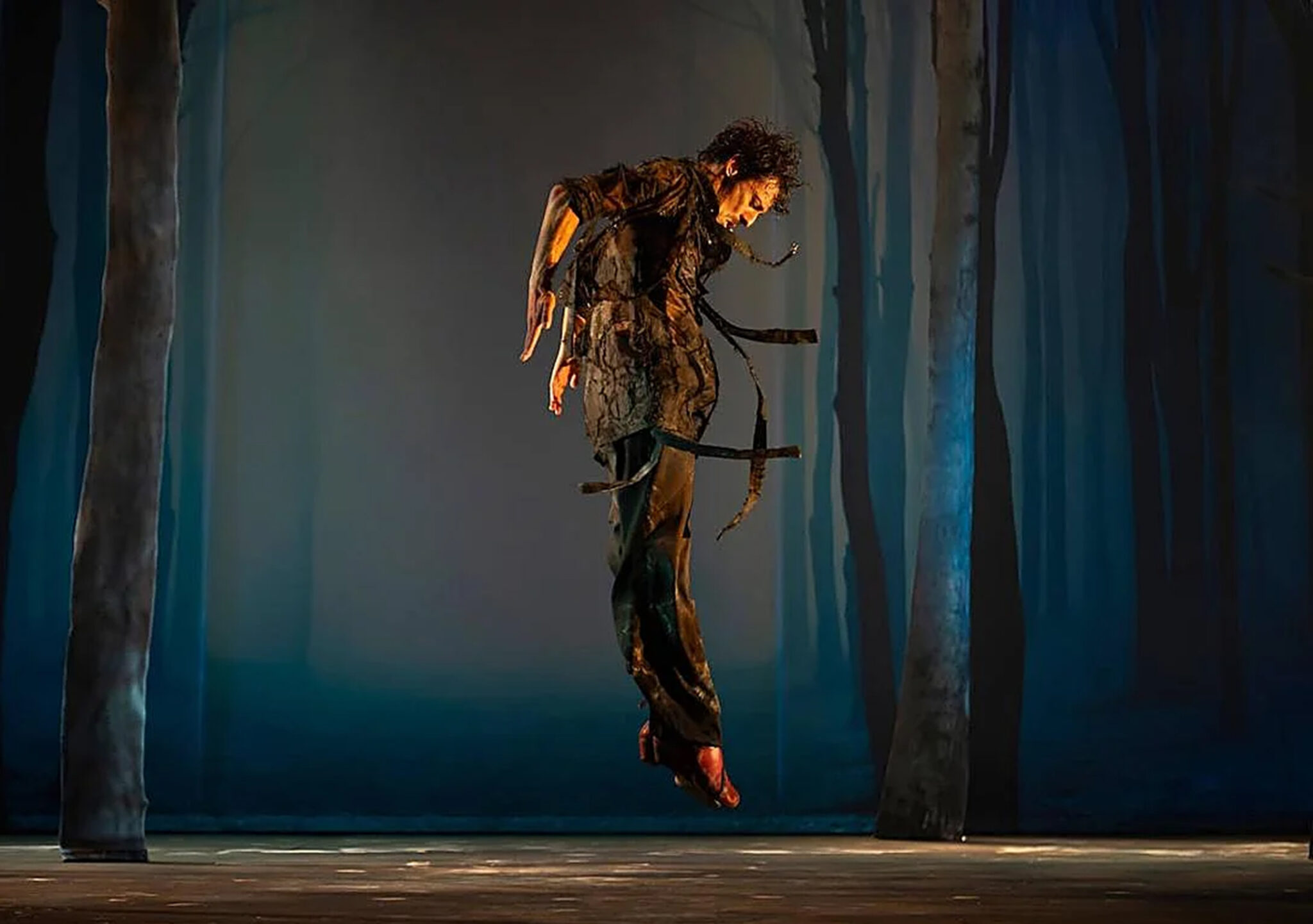 Jesús Carmona en pleine performance de Baile de Bestias, corps incliné, bras tendus et expression intense, éclairage dramatique sur scène évoquant la force et l’émotion du flamenco contemporain.