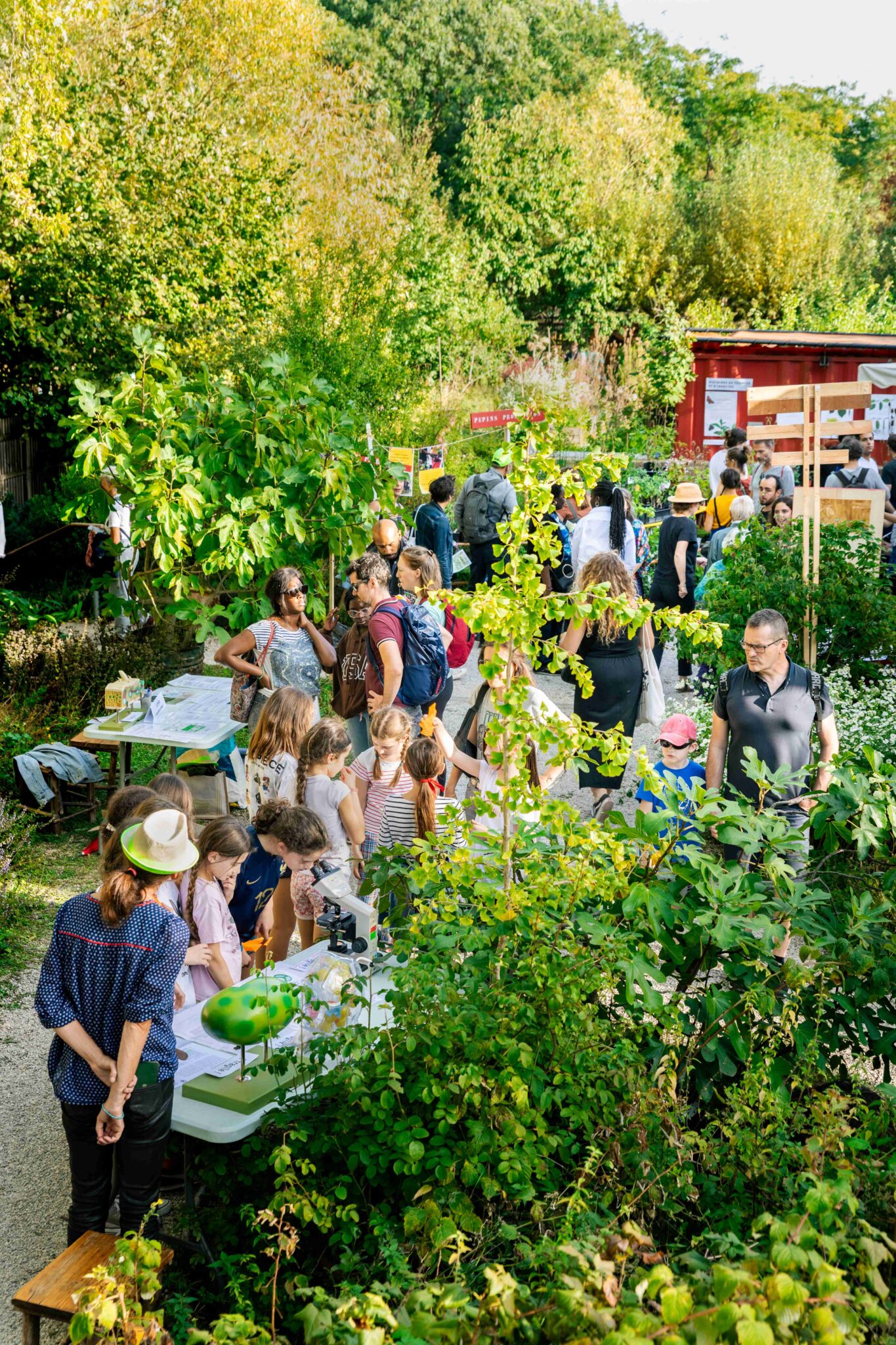 Familles et enfants participant à un atelier en plein air dans un jardin verdoyant pendant un festival