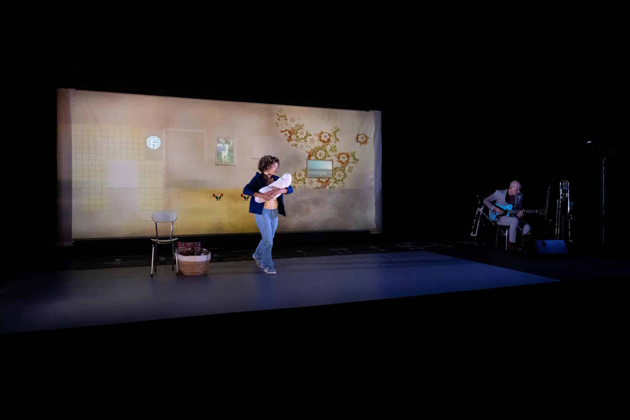 Une interprète porte un poupon sur scène tandis qu’un musicien joue de la guitare, dans le spectacle La Petite Tuk de Oh ! Oui Joachim Latarjet et Alexandra Fleischer.