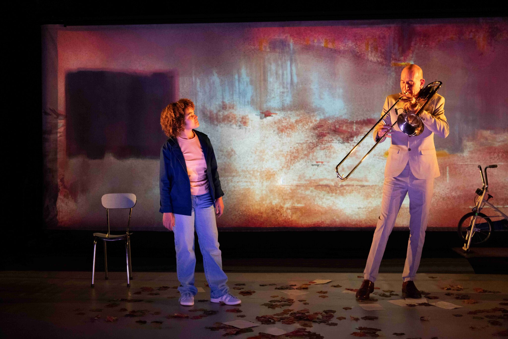 Une interprète et un musicien au trombone sur scène, devant une projection colorée, dans le spectacle La Petite Tuk de Oh ! Oui Joachim Latarjet et Alexandra Fleischer.