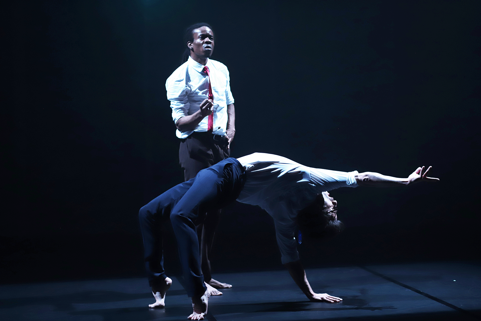 Deux interprètes, Julien Derouault et Dexter, se font face sur une scène sombre, séparés par un faisceau laser rouge. Leurs corps sont tendus dans une posture de confrontation, entre danse et tension dramatique.