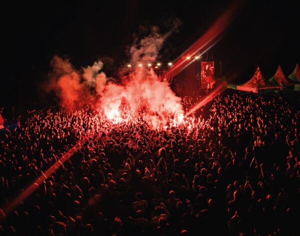 Foule dense en concert nocturne illuminée par une torche rouge