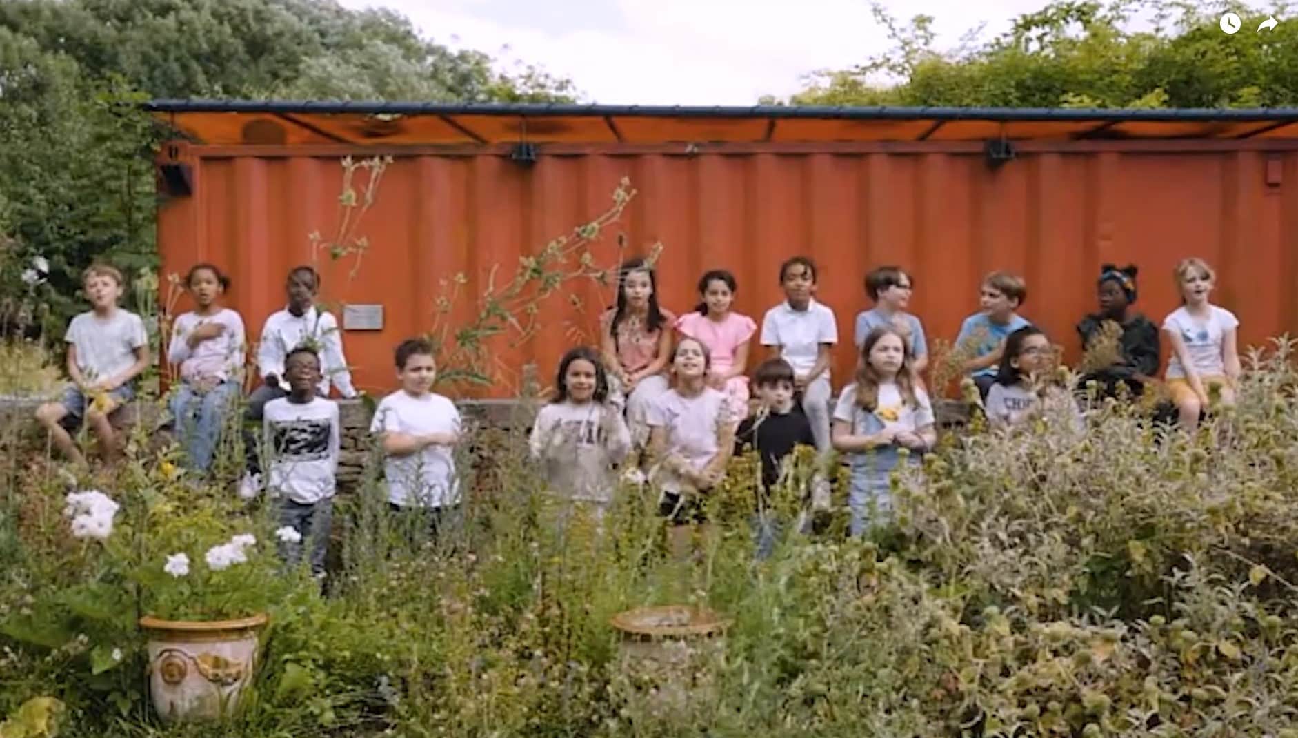Groupe d’enfants participant à un atelier en plein air dans le jardin de La Villette, devant un conteneur orange.