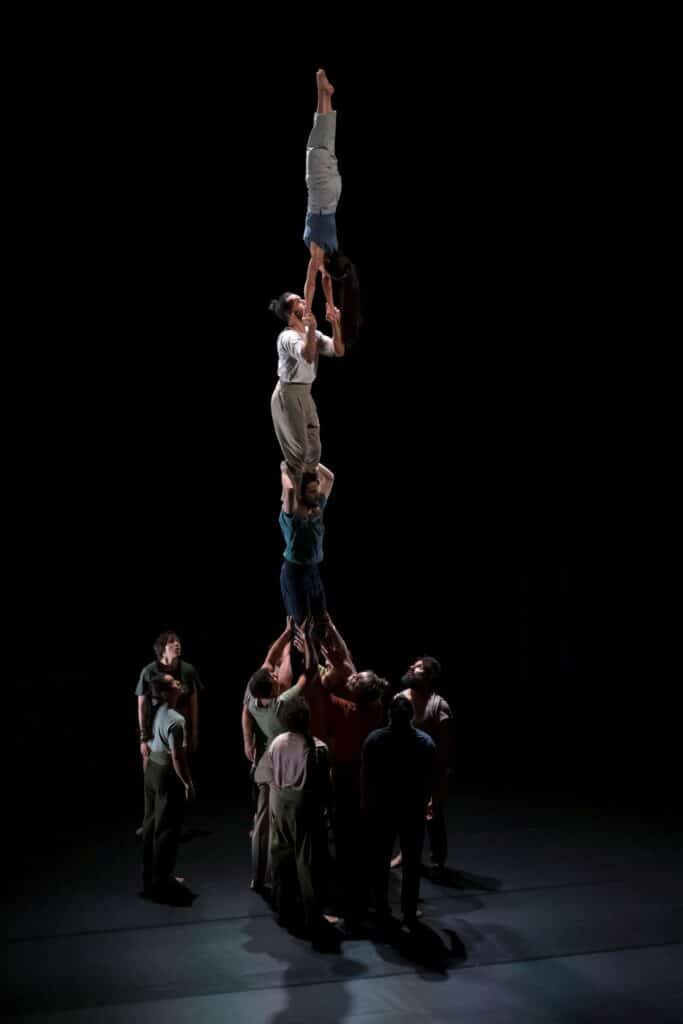 Spectacle de cirque contemporain à La Villette : une pyramide humaine impressionnante où des acrobates forment une tour verticale.