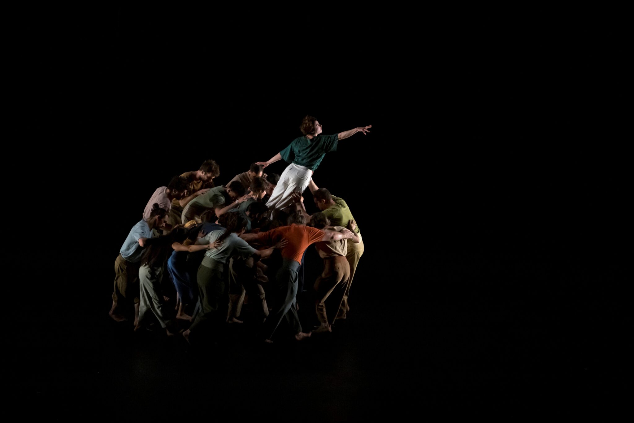 Spectacle à La Villette : un groupe d’acrobates forme une masse compacte d’où émerge un artiste tendant le bras vers le ciel.