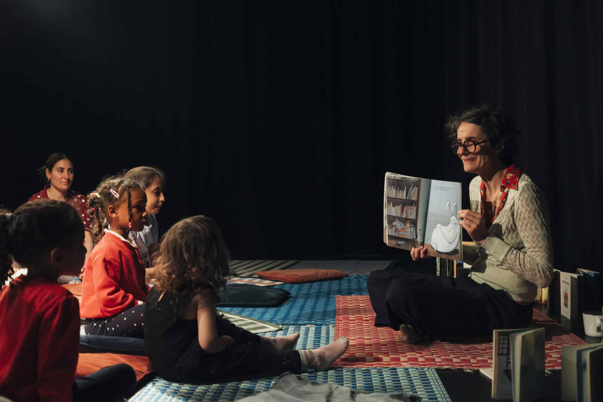 Enfants installés sur des coussins écoutant la conteuse lors de l’atelier Au Creux de l’Oreille à La Villette.