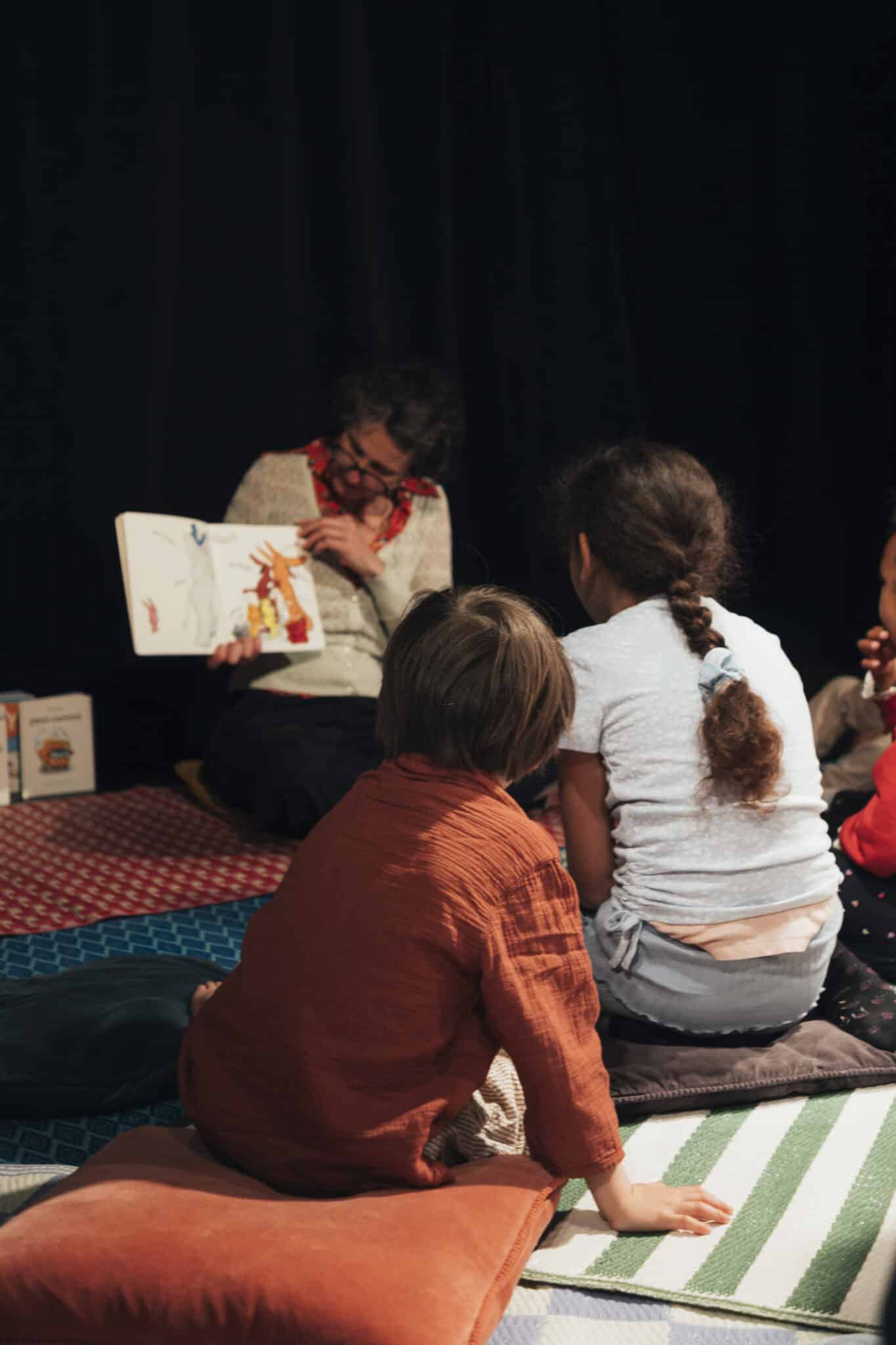 Enfants installés sur des coussins écoutant la conteuse lors de l’atelier Au Creux de l’Oreille à La Villette.
