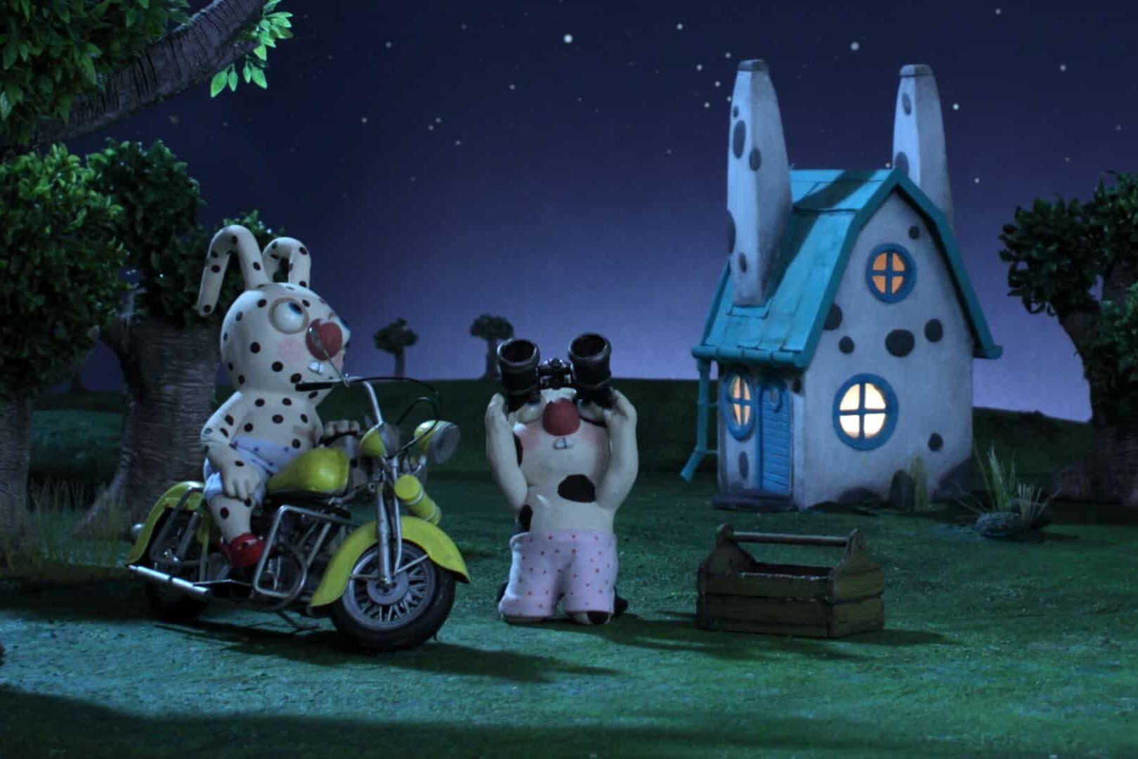 Deux lapins observent les étoiles, à côté de leur maison. L'un est sur une moto, l'autre a des jumelles.