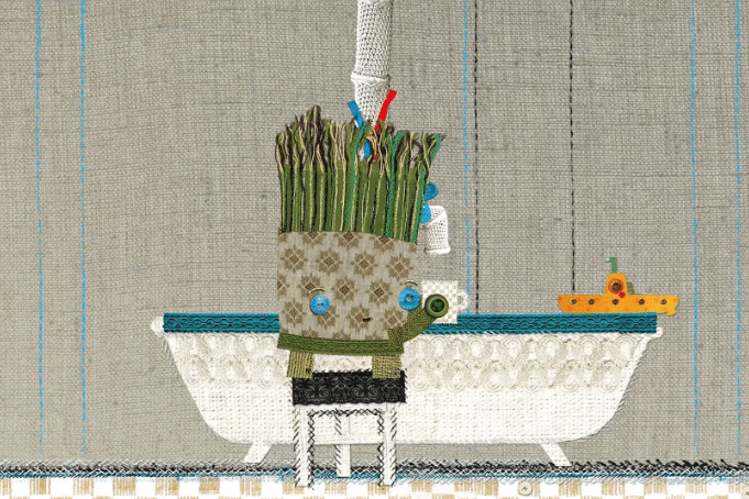 Personnage en tissu avec une tête d’asperges se tenant devant une baignoire.