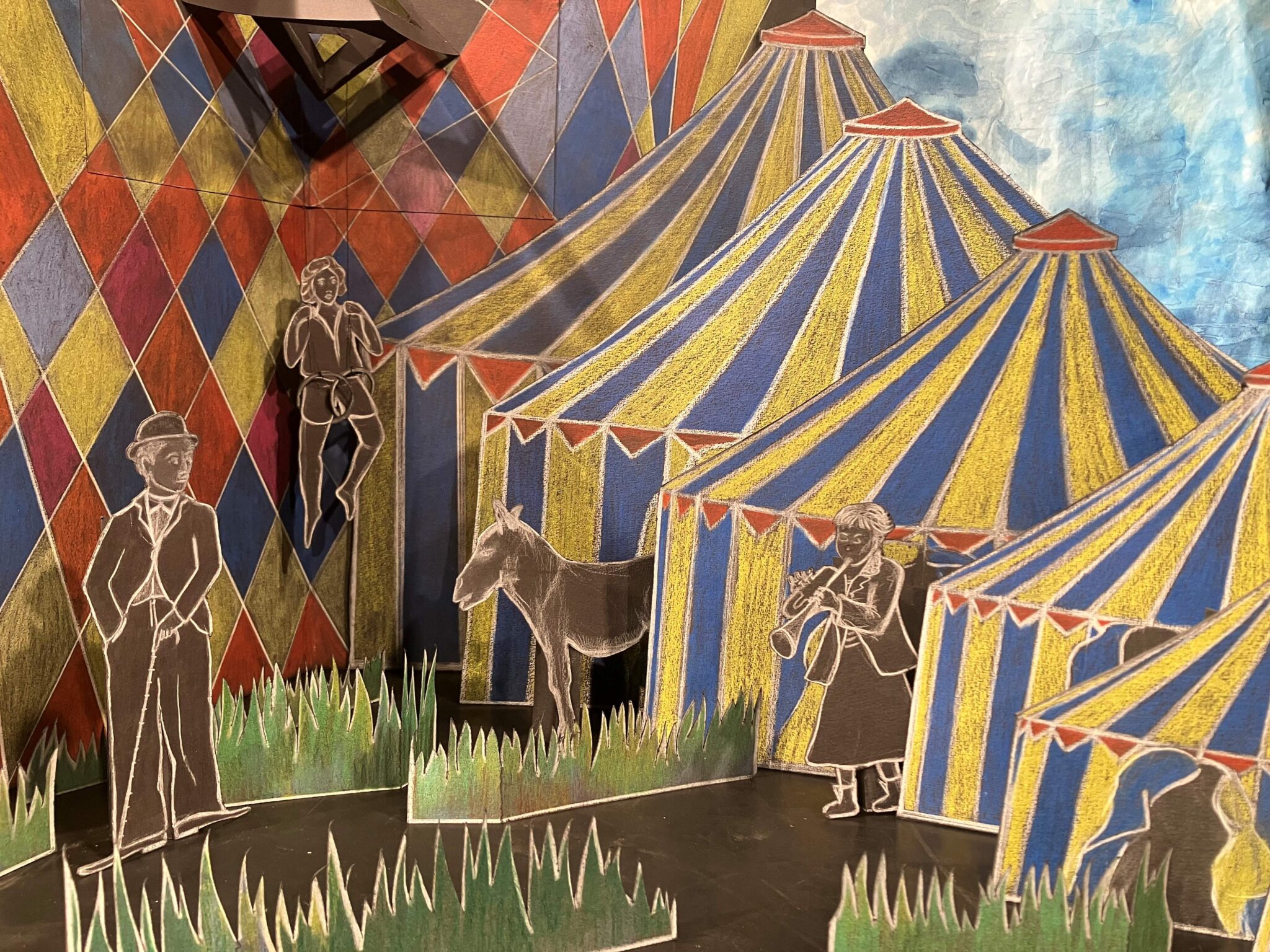 Le Cirque de papier : décor en papier représentant des chapiteaux colorés, des personnages découpés et un âne, disposés comme une scène de cirque miniature.