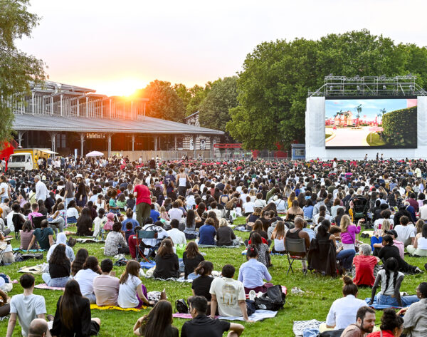 Vue du cinéma en plein air à La Villette avec une grande foule sur la pelouse.