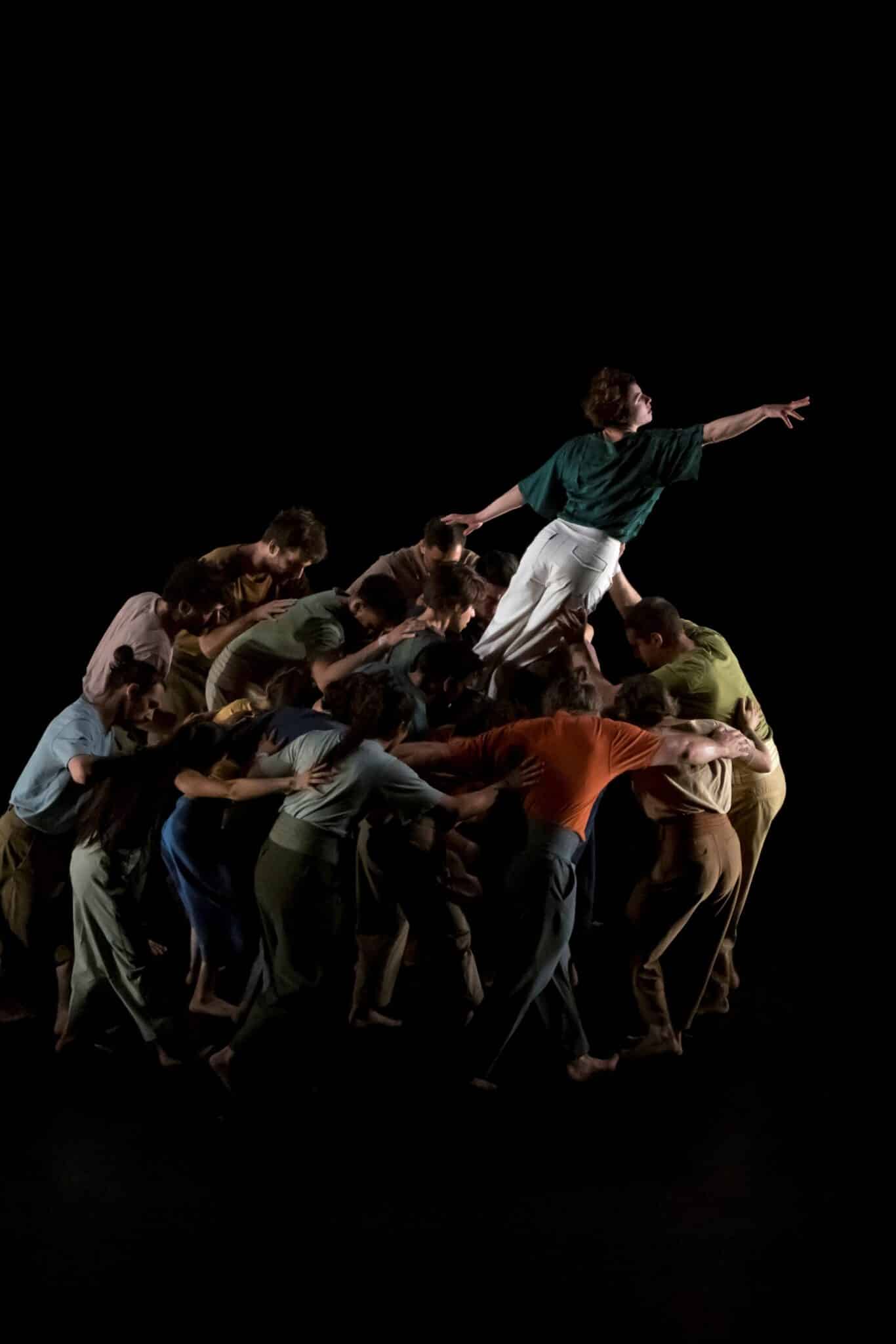 Spectacle à La Villette : un groupe d’acrobates forme une masse compacte d’où émerge un artiste tendant le bras vers le ciel.